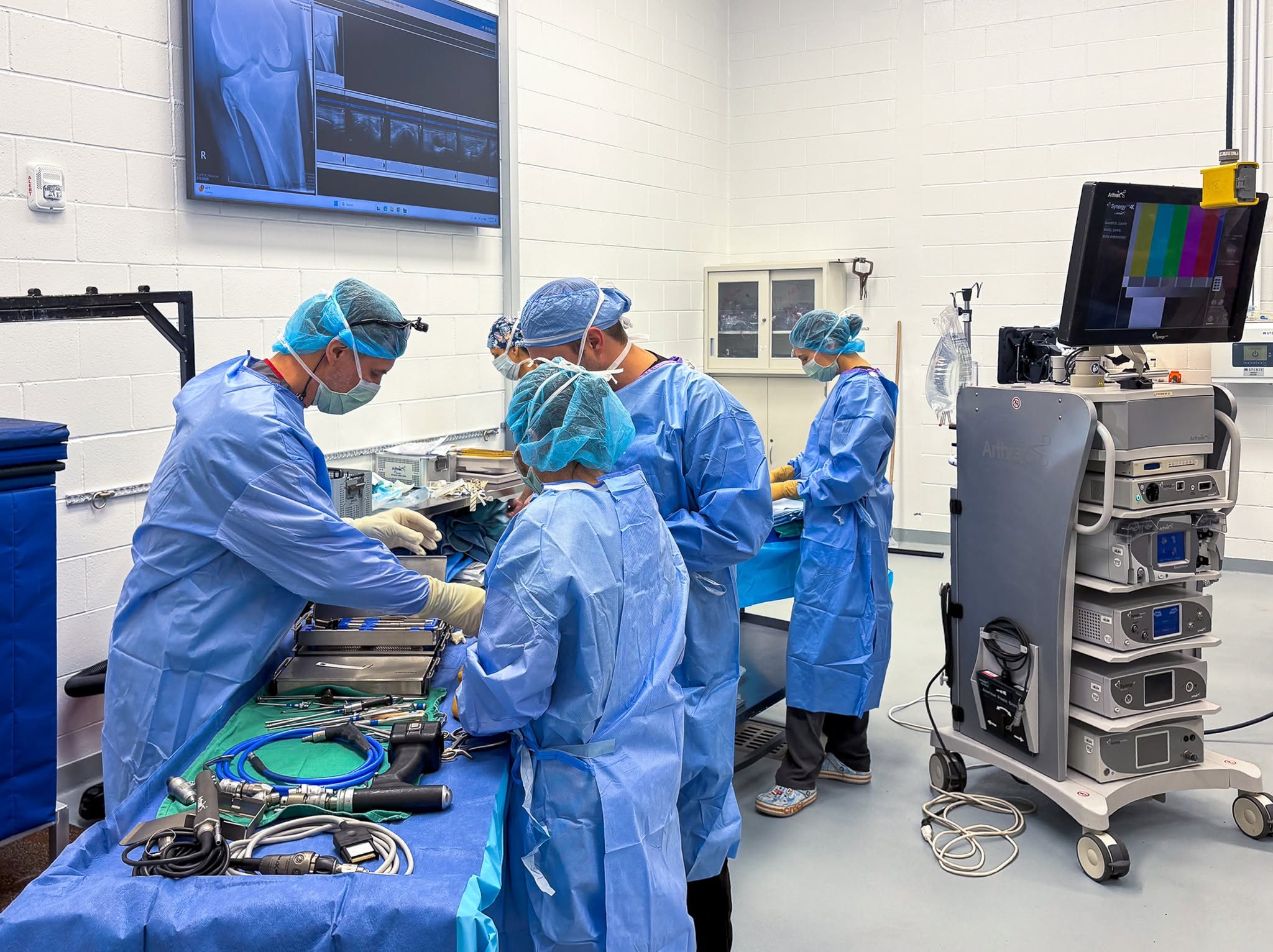 OR team at work, instrument table, imaging monitors and X-ray visible in background